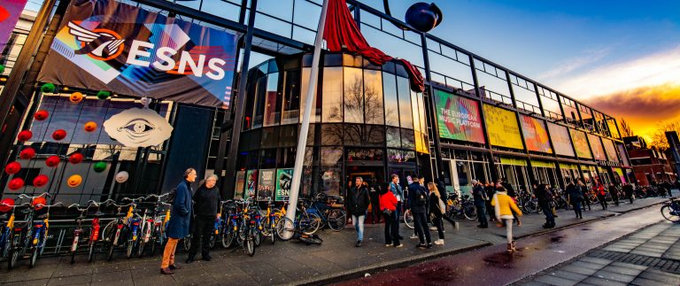 Gevel van De Oosterpoort met kleurrijke lucht op de achtergrond.