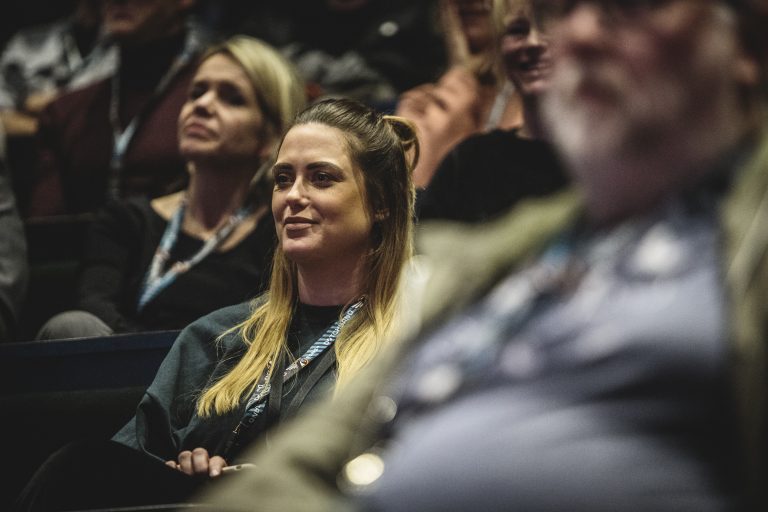 Conferentiebezoekers kijkend naar een seminar.