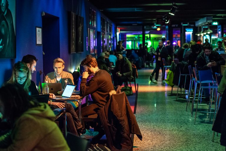 Conferentie in De Oosterpoort met tafeltjes en conferentiebezoekers