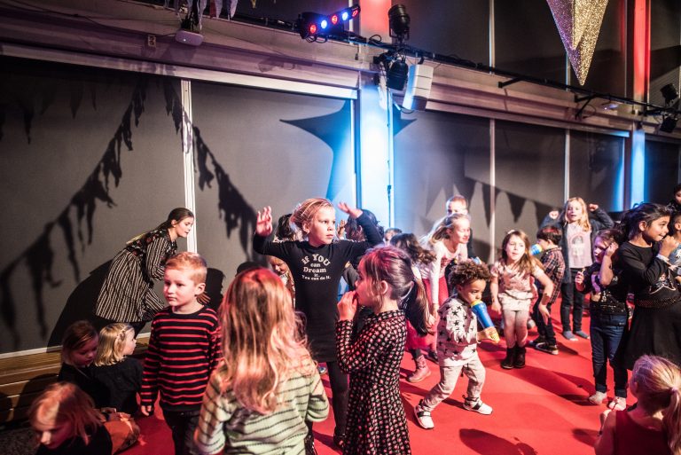 Verschillende kinderen dansend en spelend op een rode vloer