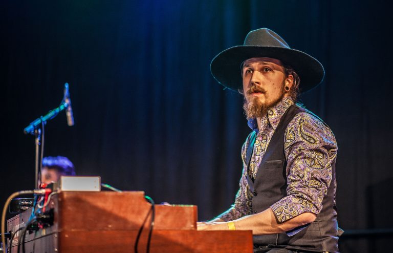 Man in pak met een hoed op zijn hoofd spelend op de piano