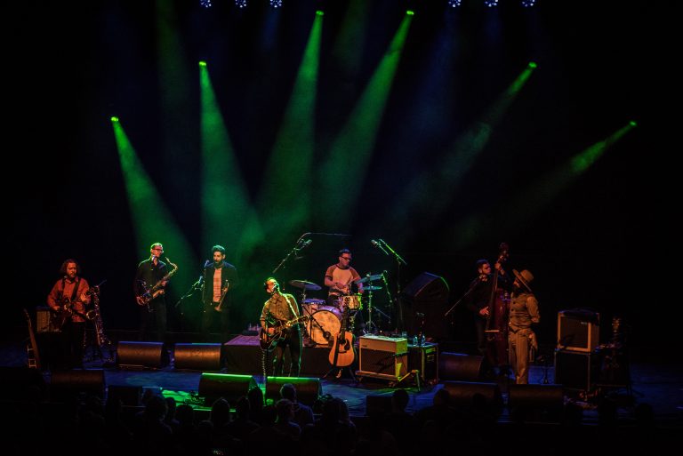Een band speelt live op het podium met groene lichten.