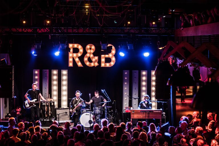 Een band speelt op een podium met een grote