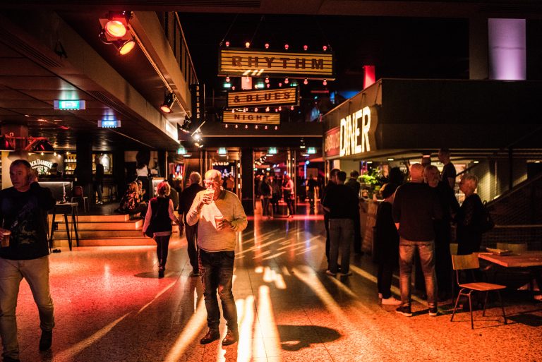 Een levendige uitgaansgelegenheid met felgekleurde verlichting en een menigte mensen die genieten van de sfeer.