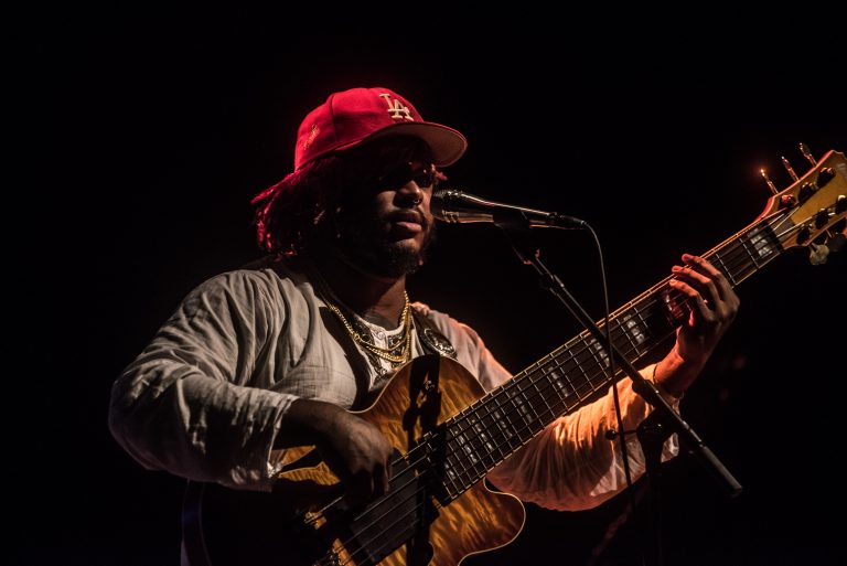 Een muzikant speelt op een gitaar en zingt in een duidelijke, sfeervolle belichting.