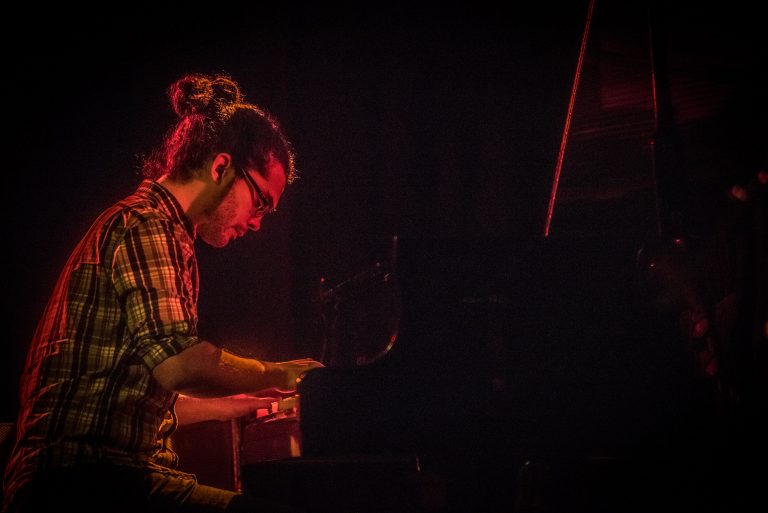 Een muzikant speelt pianomuziek onder sfeervolle verlichting.