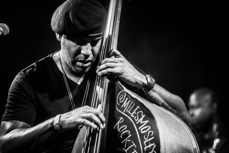 Een muzikant speelt een contrabas tijdens een optreden in zwart-wit.