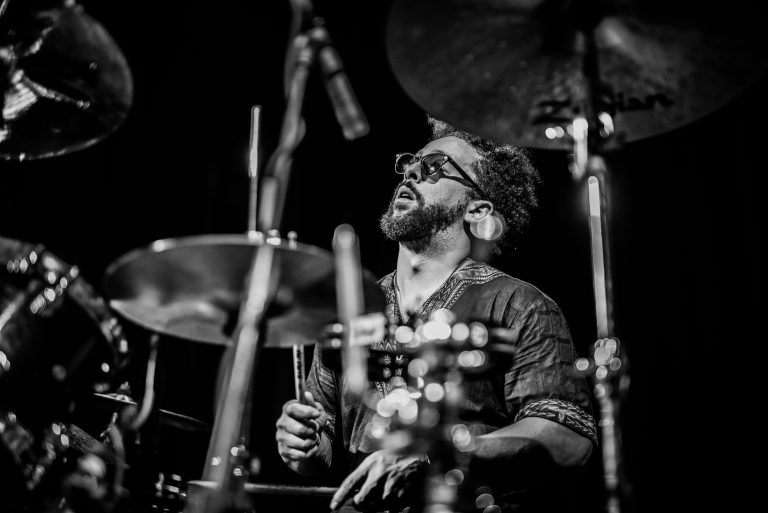 Een drummer die enthousiast speelt op een drumstel in zwart-wit.