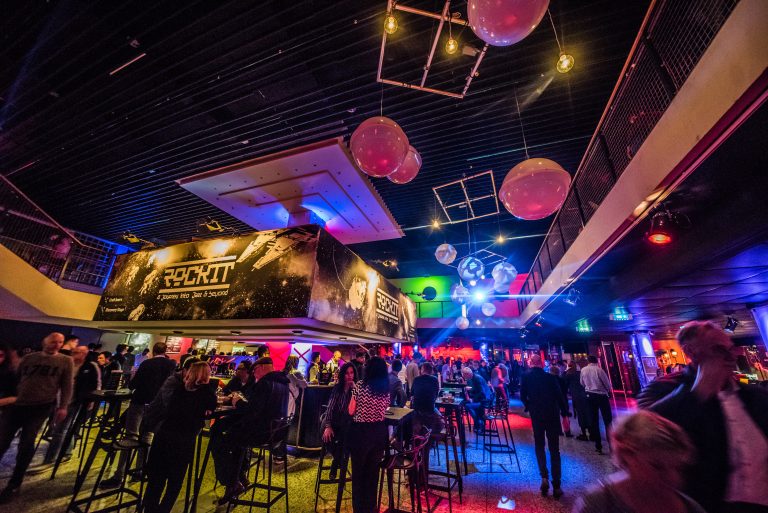 Een levendig interieur van een club met sfeerverlichting en mensen die genieten van een avond uit.