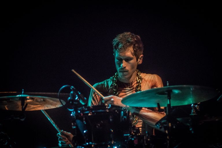 Een drummer speelt op zijn drumstel met een geconcentreerde blik.