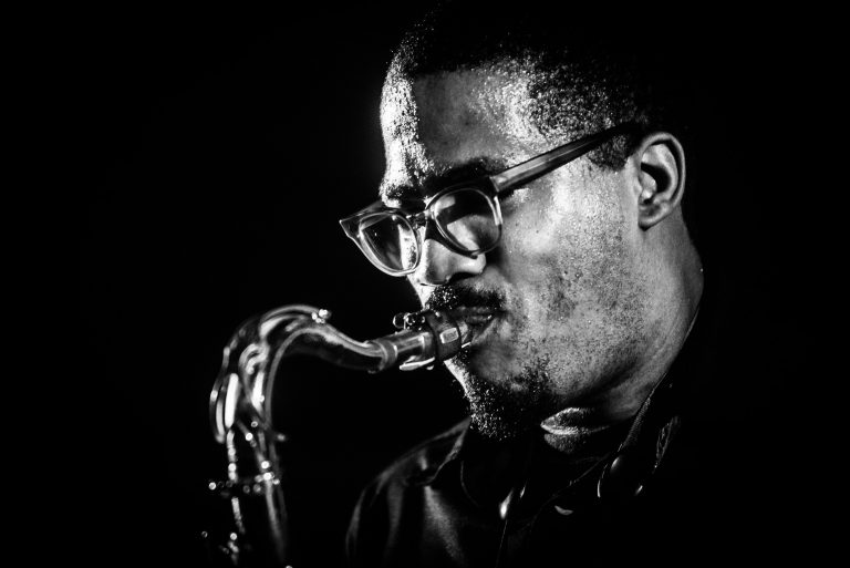 Een man speelt saxofon in zwart-wit verlichting.