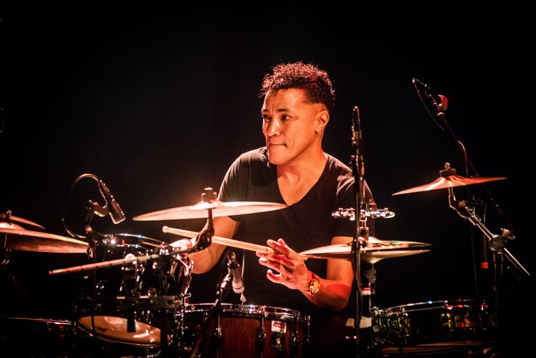 Een drummer speelt energiek op een drumstel tijdens een live optreden.