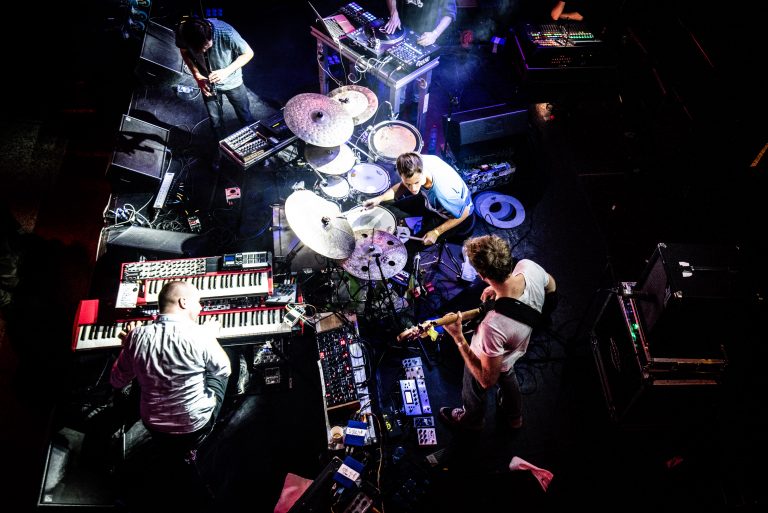 Een overheadfoto van een muzikale live-optreden met verschillende muzikanten die instrumenten bespelen.