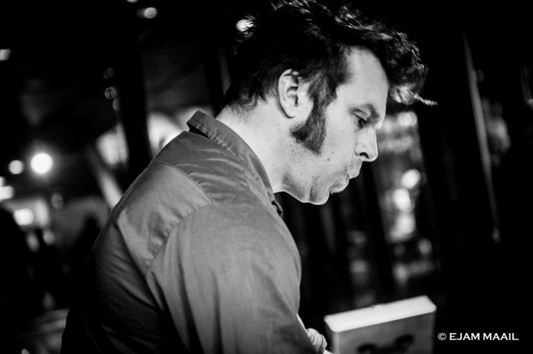 Zwart-witfoto van een man in profiel die geconcentreerd naar beneden kijkt.