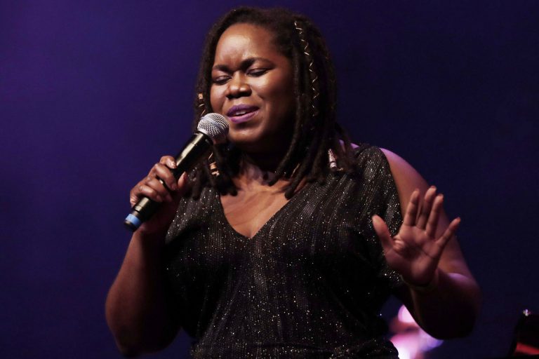 Zangeres met een microfoon in de hand, terwijl ze zingt op het podium.