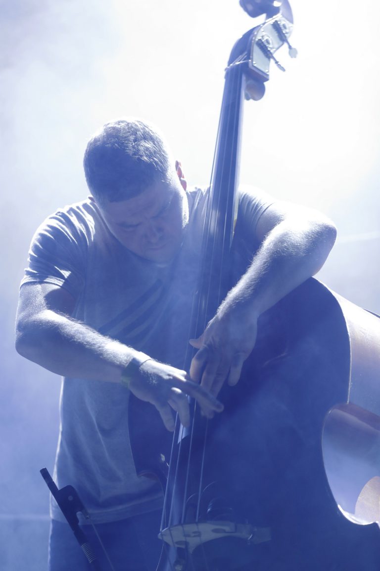 Een muzikant speelt een contrabas op een mistig podium.