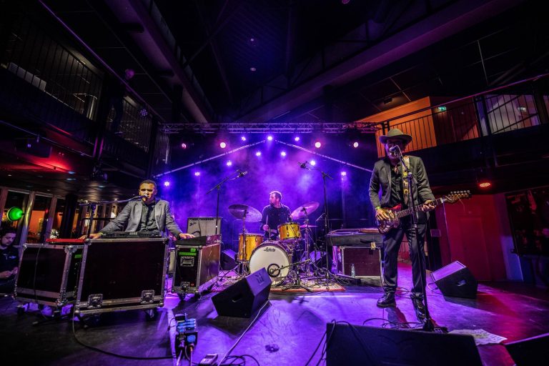 Een live band speelt op een podium met kleurrijke verlichting.