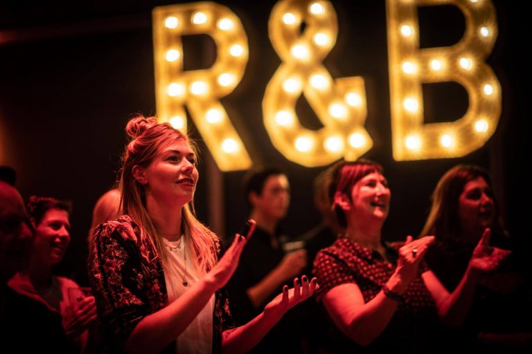Twee vrouwen genieten van muziek onder een sfeervolle verlichting met de letters