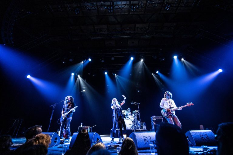 Een live band die optreedt op een podium met blauwe lichten.