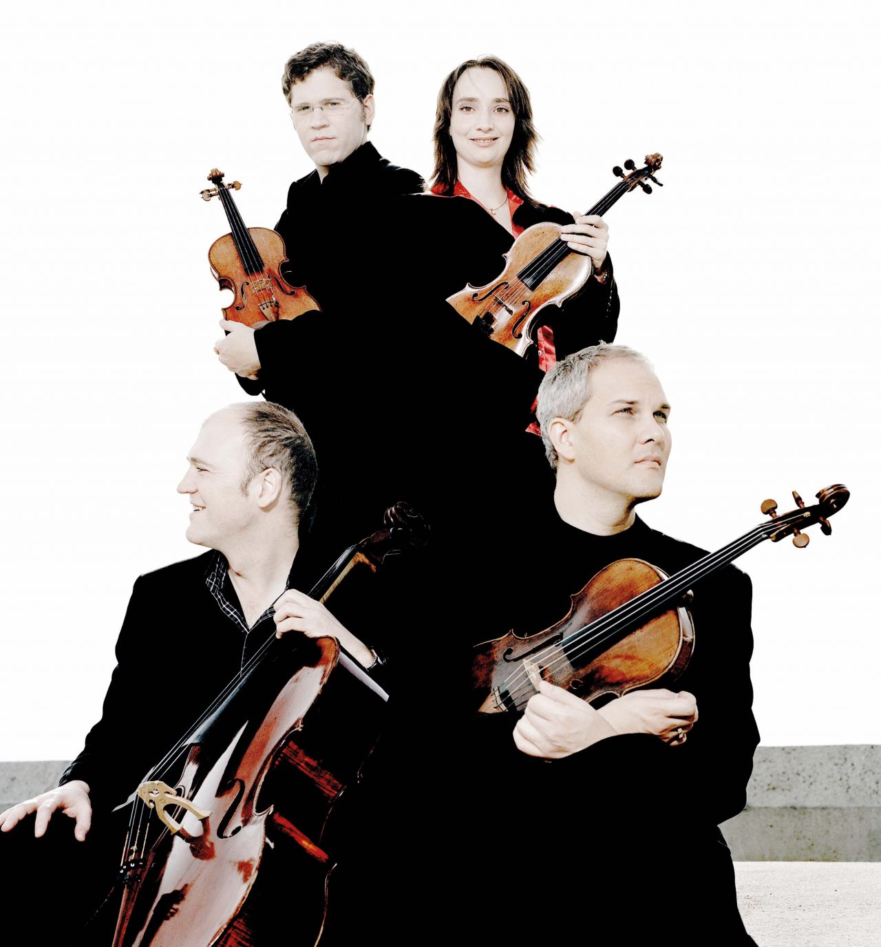 Een groep van vier muzikanten poseert met strijkinstrumenten tegen een lichte achtergrond.