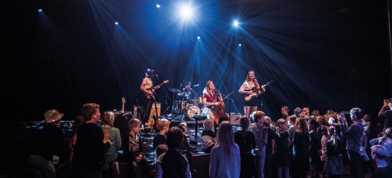 Band op het podium speelt muziek terwijl er kinderen kijken