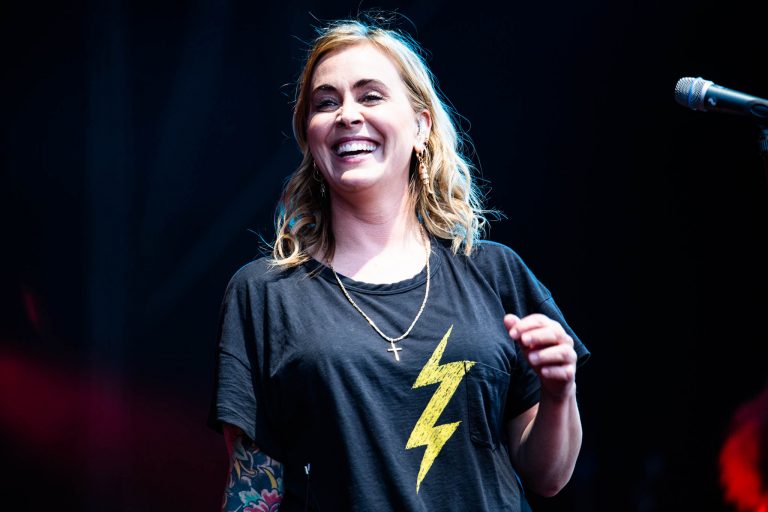 Een glimlachende persoon in een zwart T-shirt met een gele bliksemschicht erop.