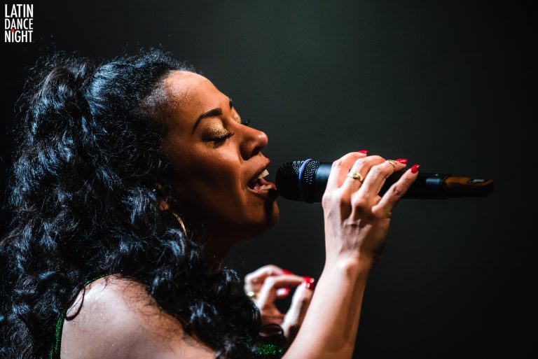 Een zangeres die met passie een microfoon vasthoudt tijdens een optreden.