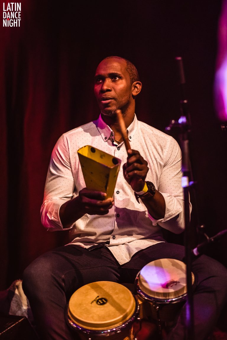 Een man speelt op een percussie-instrument terwijl hij op een podium zit.