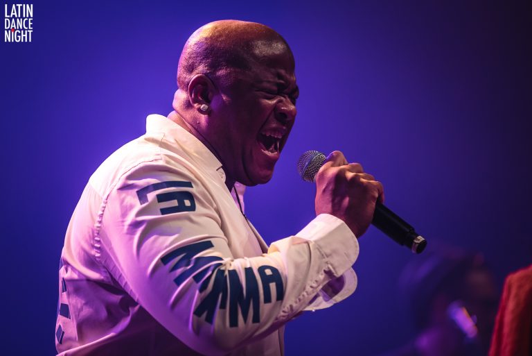 Een zanger met een microfoon in de hand, intens aan het optreden op het podium.