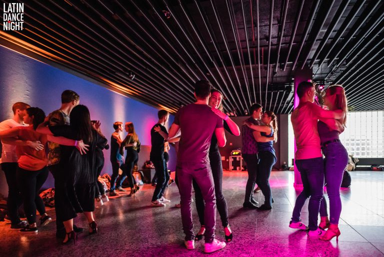 Een groep mensen danst samen in een moderne, sfeervol verlichte ruimte.