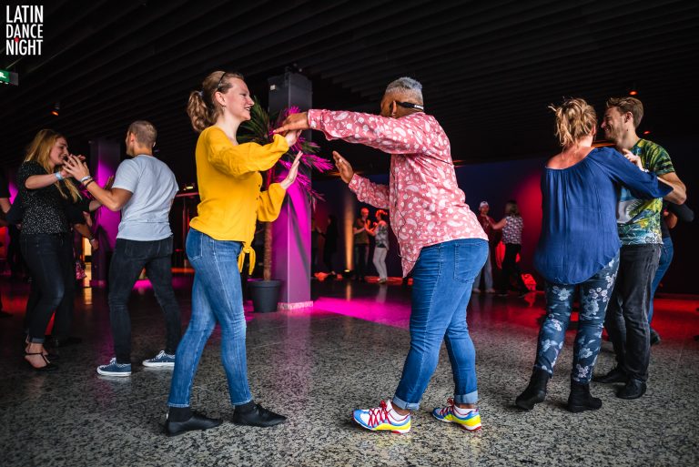 Twee vrouwen zijn aan het dansen in een levendige omgeving met kleurrijke lichten.