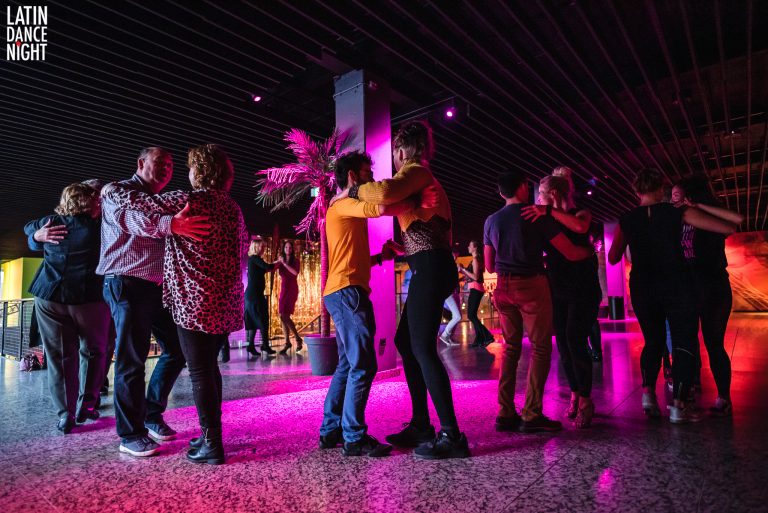 Mensen dansen in een sfeervolle ruimte met kleurrijke verlichting.