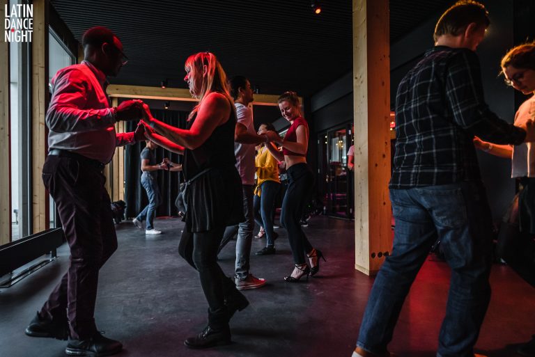 Mensen dansen samen op een podium met sfeerverlichting.
