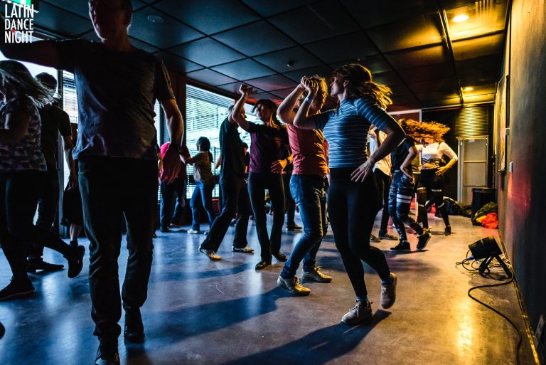 Een groep mensen danst in een sfeervolle ruimte met gedimd licht.
