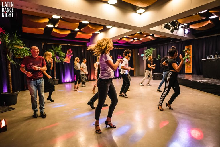 Een groep mensen danst samen in een sfeervolle ruimte met kleurrijke verlichting.