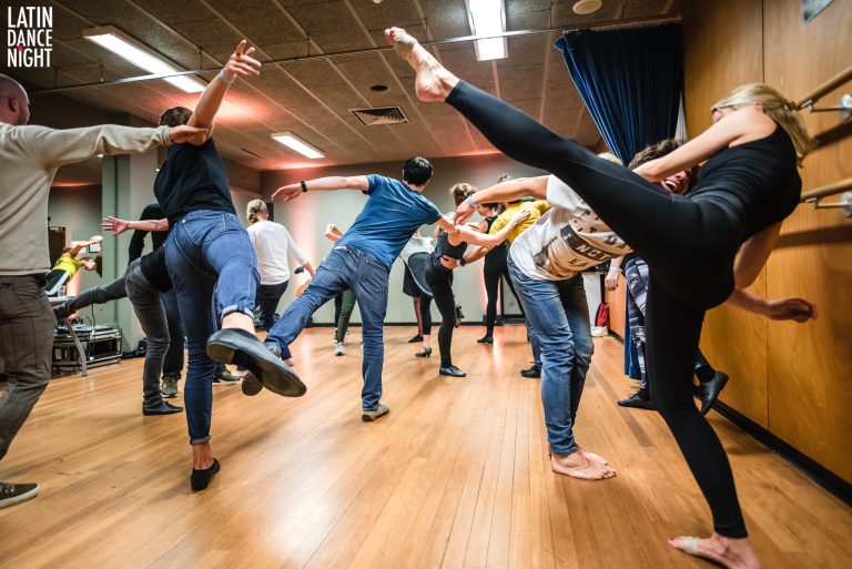 Groep mensen in een dansles, waarbij verschillende danshoudingen worden aangenomen.