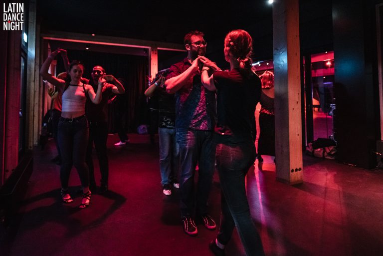 Mensen dansen in een sfeervolle, lichtgevende ruimte.