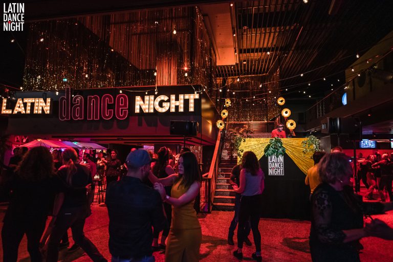 Een levendige dansnacht met mensen die dansen en een sfeervolle setting met kleurrijke verlichting en decoraties.