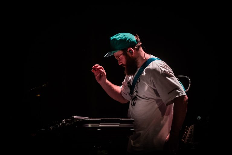 Een muzikant speelt op een elektronisch apparaat in een donkere omgeving.