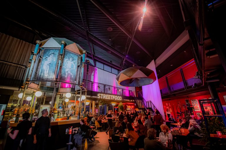 Een levendige baromgeving met kleurrijke verlichting en bezoekers die genieten van hun tijd.