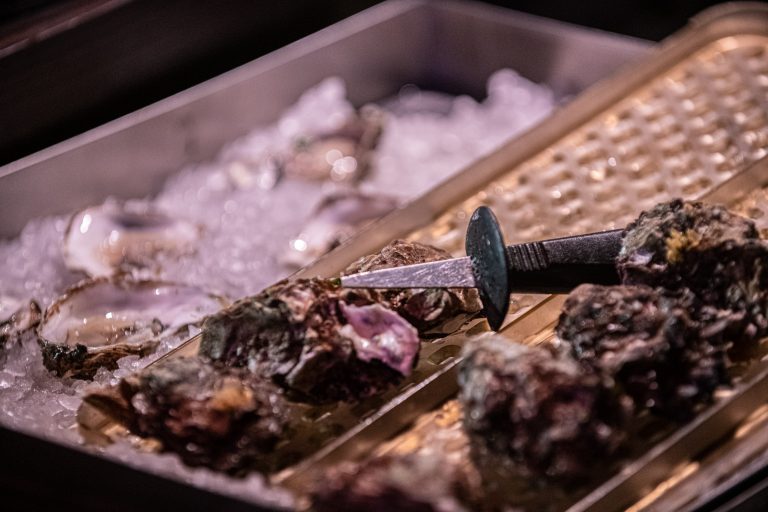 Oesters liggen op ijs met een scheermesje ernaast.