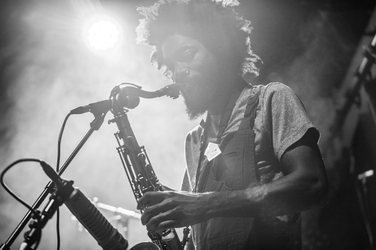 Een muzikant speelt saxofon in een sfeervolle, licht gemiste omgeving.