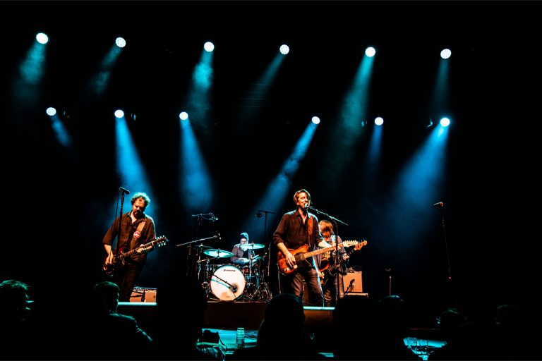Een band performt op een podium met felblauwe lichten.