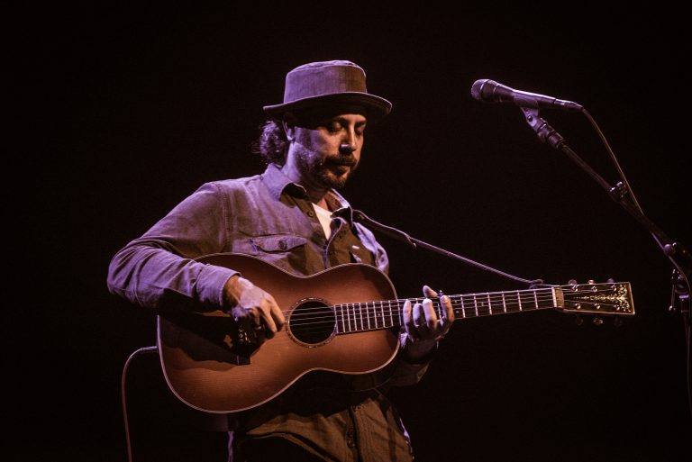 Een muzikant speelt op een akoestische gitaar tijdens een optreden op het podium.
