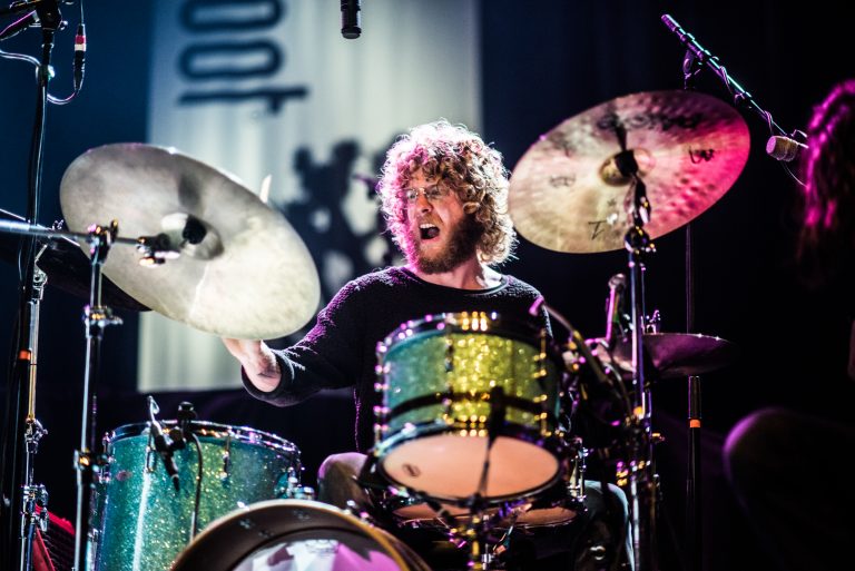 Een drummer speelt energiek op zijn kleurrijke drumstel tijdens een live optreden.