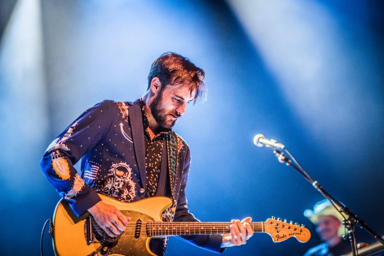 Muzikant speelt op een elektrische gitaar onder kleurrijke podiumverlichting.