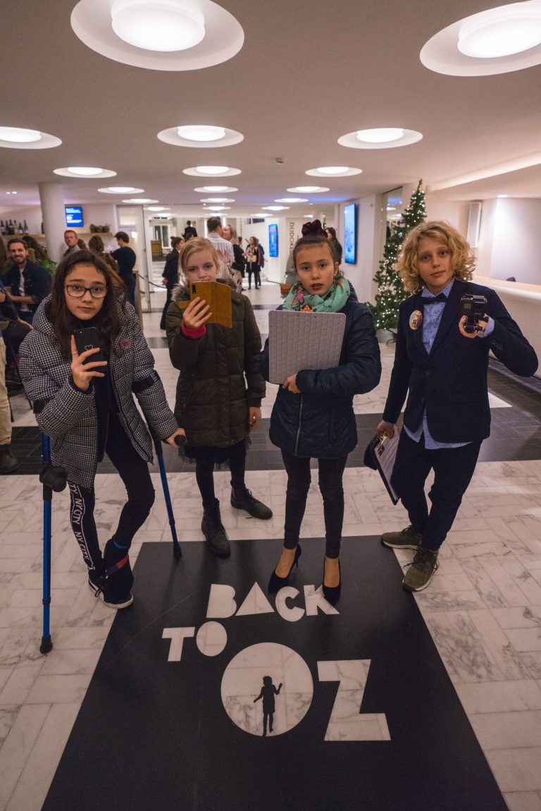 Een groep kinderen poseert in een gang bij een evenement met de tekst