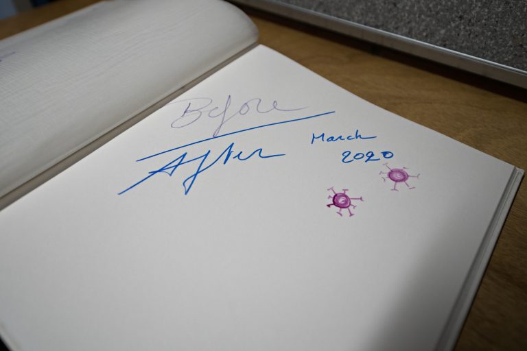 Een open pagina van een notitieboek met een handtekening en datums, naast enkele handgetekende virus-illustraties.