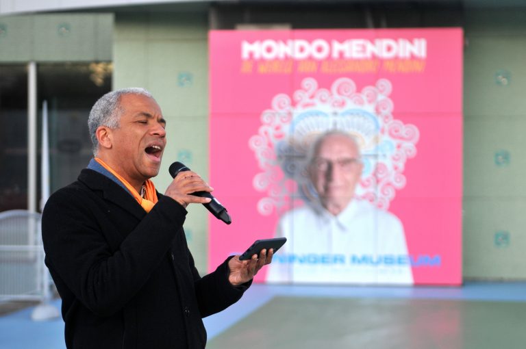 Een man zingt en houdt een smartphone vast voor een kleurrijk achtergrondontwerp.