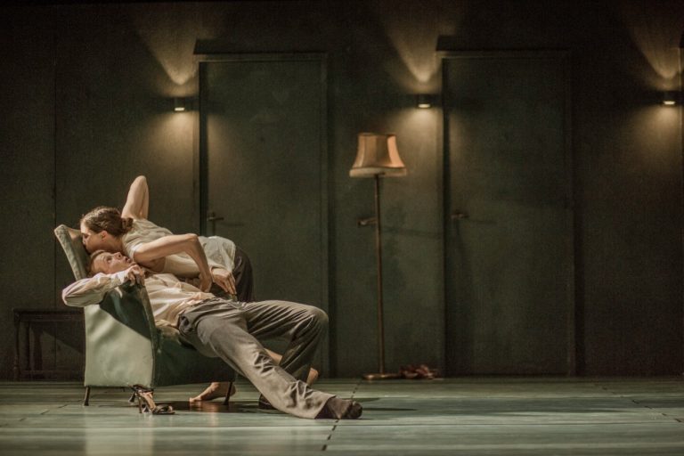 Een man en een vrouw zitten ontspannen in een ruimte met een groene wand en sfeerverlichting.